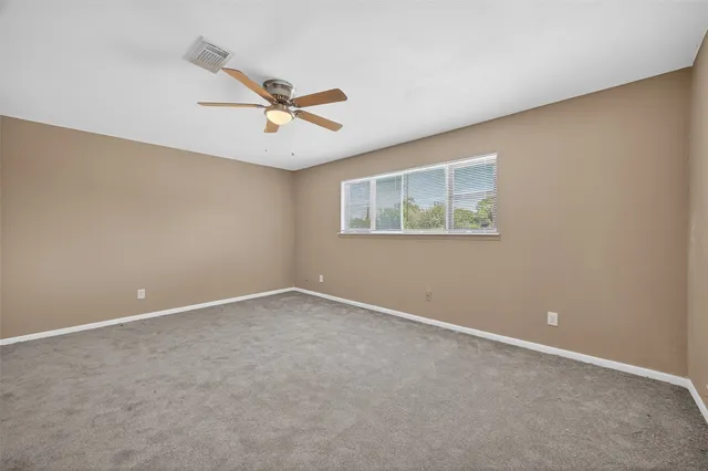 an empty room with a window and a ceiling fan