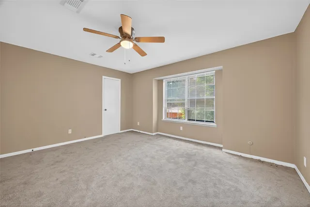 an empty room with windows and fan
