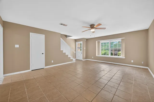 an empty room with chandelier fan and windows