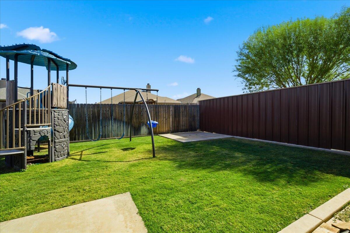 9807 Virginia Avenue Lubbock, TX 79424 - Photo 37 of 39 a view of a backyard with a slide trees and wooden fence