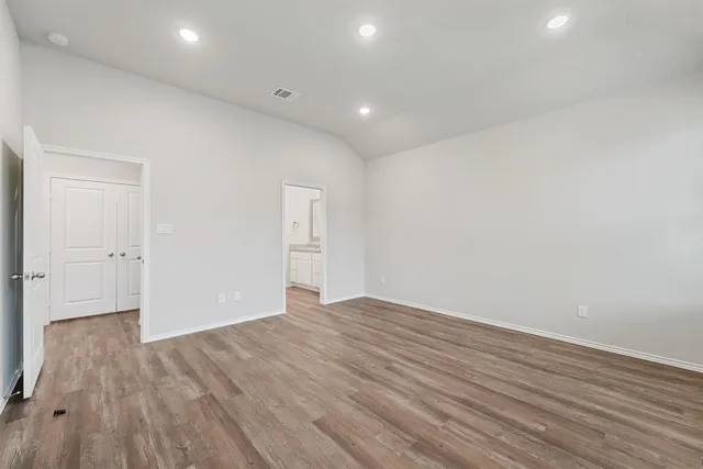 a view of an empty room with wooden floor and closet