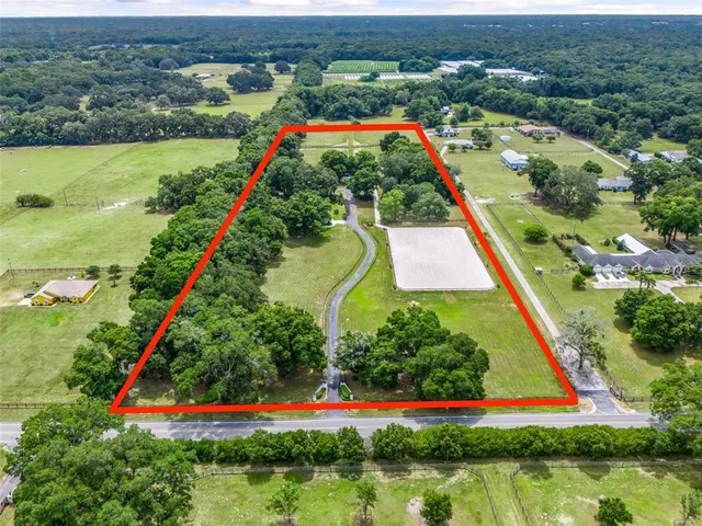 a view of a street with a small yard and large trees