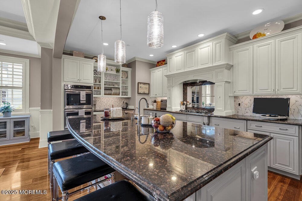 1222 Oval Road Manasquan, NJ 08736 - Photo 28 of 77 a kitchen with stainless steel appliances granite countertop a stove top oven a sink dishwasher a dining table and chairs with wooden floor