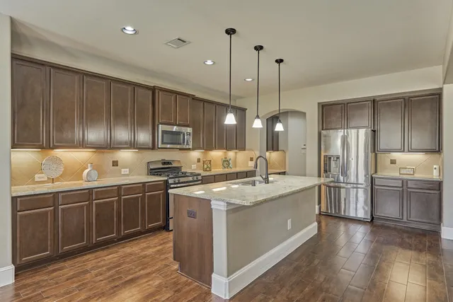 a kitchen with stainless steel appliances granite countertop a sink a stove and refrigerator
