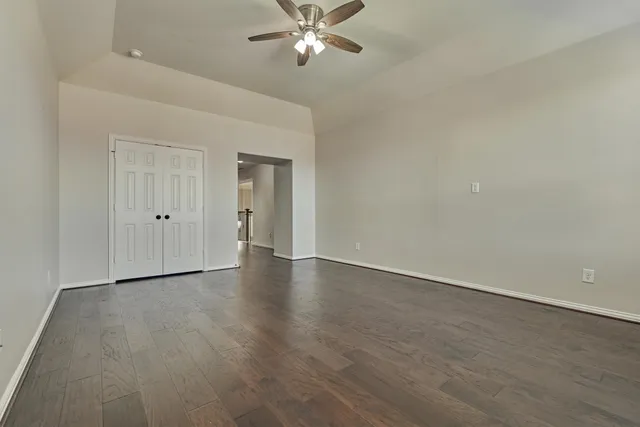 a view of an empty room with chandelier fan and windows