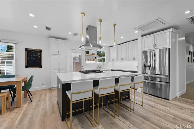 a kitchen with stainless steel appliances a dining table chairs stove refrigerator and microwave