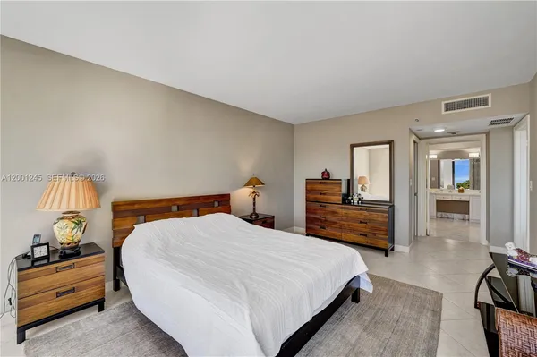 a bedroom with a bed and a potted plant on the dresser