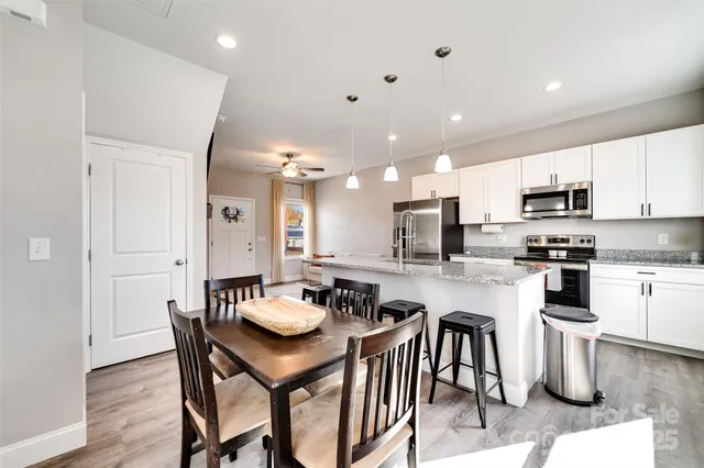a kitchen with a dining table chairs wooden floor appliances and cabinets