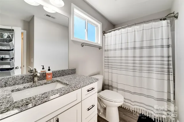 a bathroom with a granite countertop sink toilet and shower