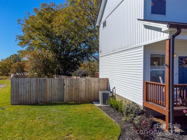 a view of a backyard with wooden fence and a tree