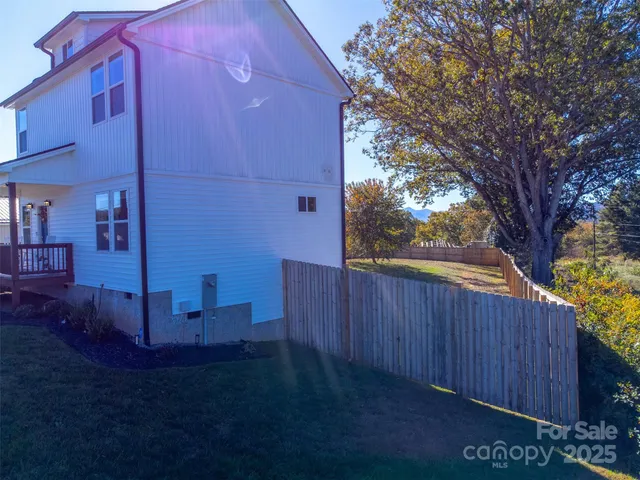 a view of backyard with wooden fence and large trees