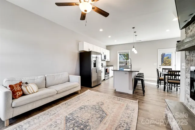 a living room with furniture kitchen view and a wooden floor