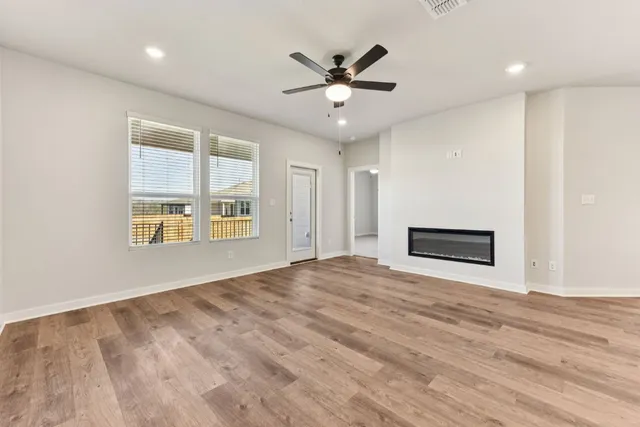 a view of an empty room with a ceiling fan and wooden floor