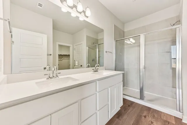 a bathroom with a double vanity sink mirror and shower
