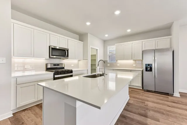 a kitchen with kitchen island a white counter top space cabinets and stainless steel appliances