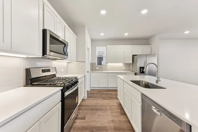 a kitchen with kitchen island granite countertop a sink and stove top oven with white cabinets
