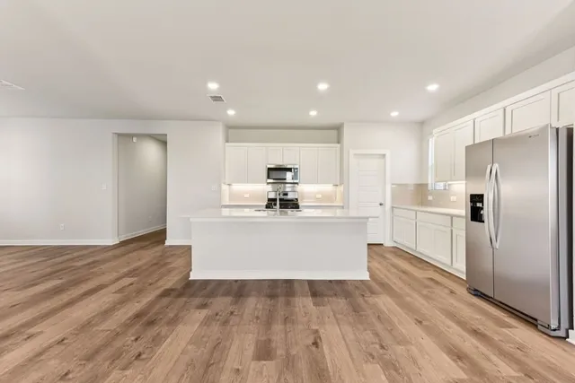 a view of kitchen with wooden floor stainless steel appliances and cabinets