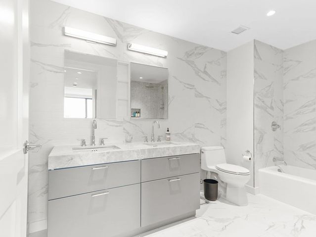 a bathroom with a double vanity sink toilet mirror and bathtub