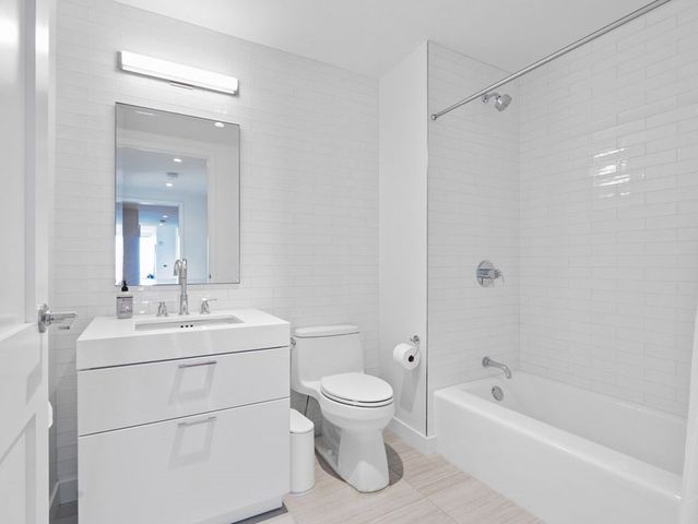 a bathroom with a toilet a sink a mirror a bathtub and vanity