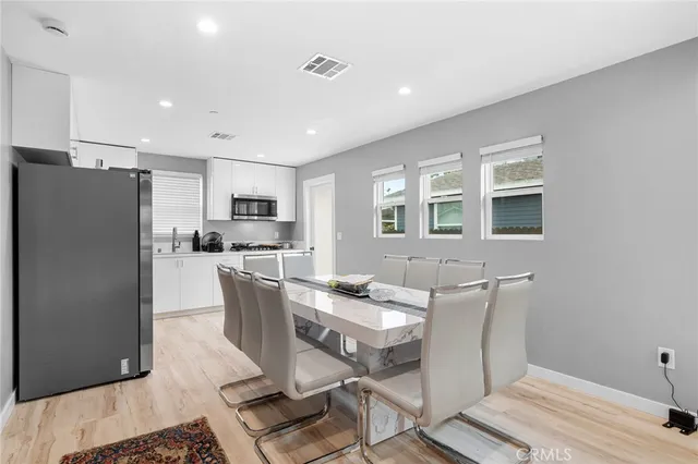 a kitchen with stainless steel appliances granite countertop a refrigerator a stove a sink a dining table and chairs