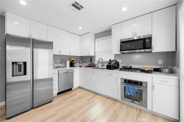 a kitchen with cabinets stainless steel appliances and wooden floor