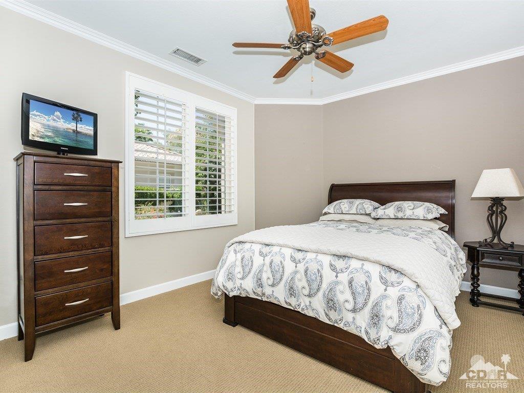 285 Loch Lomond Road Rancho Mirage, CA 92270 - Photo 21 of 48 a bedroom with a bed a chandelier and a flat tv screen on dresser