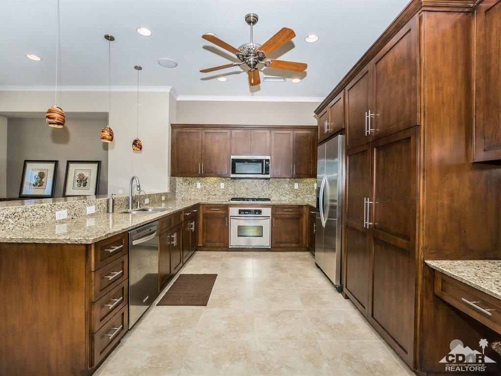 285 Loch Lomond Road Rancho Mirage, CA 92270 - Photo 10 of 48 a kitchen with stainless steel appliances granite countertop a refrigerator a sink dishwasher and a stove with wooden cabinets