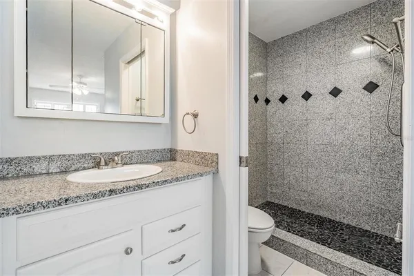 a bathroom with a granite countertop sink a toilet and shower