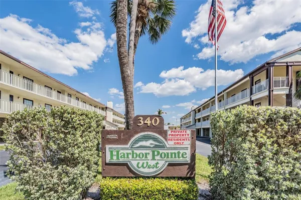 a view of a sign board with buildings in the background