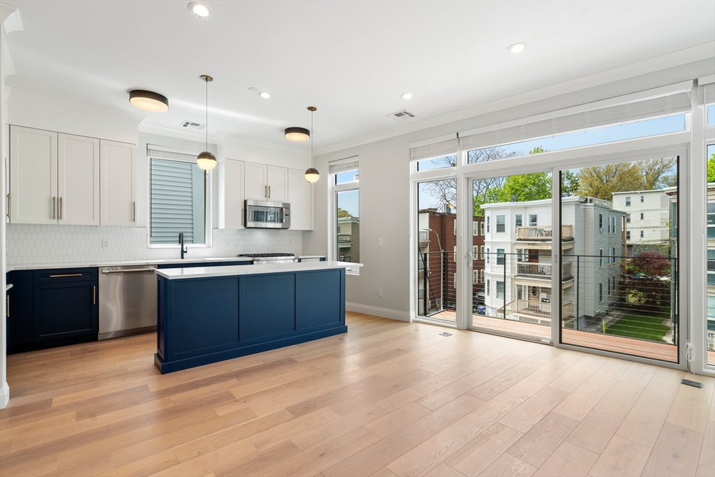 142 Pleasant Street Boston, MA 02125 - Photo 15 of 24 a large kitchen with stainless steel appliances granite countertop a large counter top a wooden floor and cabinets