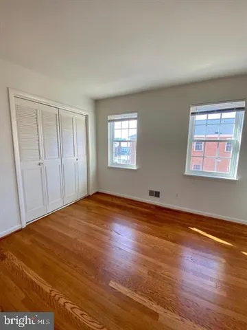 a view of an empty room with wooden floor and window