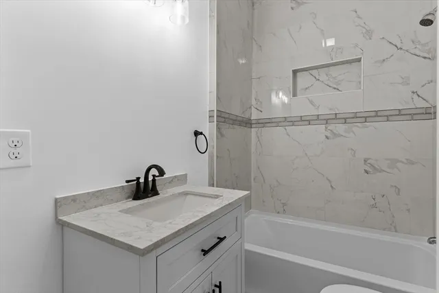 a bathroom with a granite countertop sink toilet and bathtub