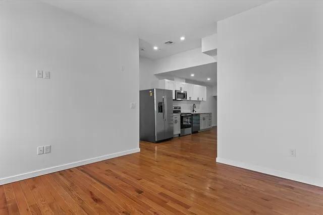 a view of a kitchen with a refrigerator and a wooden floor