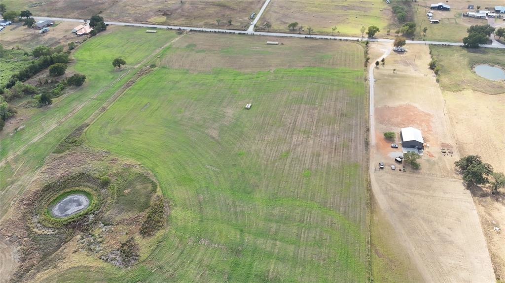 2101 Billings Road Tolar, TX 76476 - Photo 19 of 23 Expansive green fields, a small pond, an agricultural building, and a paved road