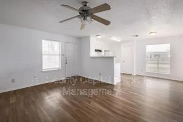 an empty room with wooden floor fan and windows