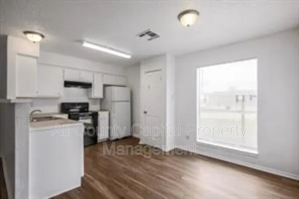 a kitchen with stainless steel appliances granite countertop a stove a refrigerator a sink and white cabinets with wooden floor