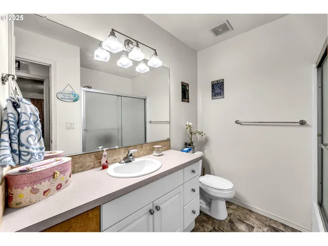 a bathroom with a sink a toilet a large mirror and shower