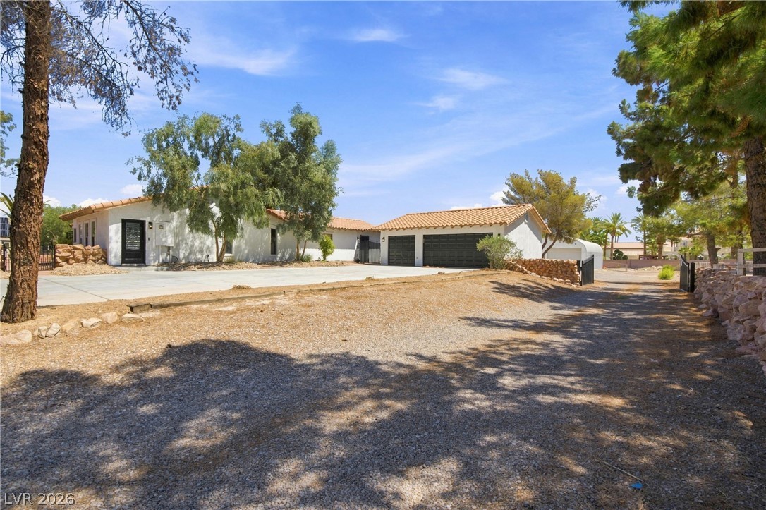 7744 Rancho Destino Road Las Vegas, NV 89123 - Photo 8 of 48 Mature trees frame a sprawling exterior featuring a tile roof and an expansive driveway.