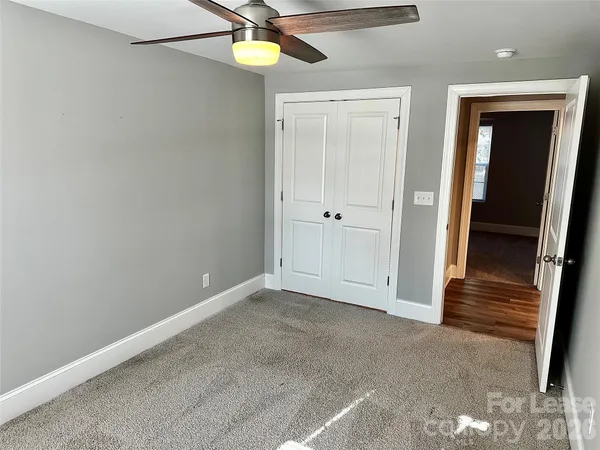 an empty room with closet and a chandelier fan