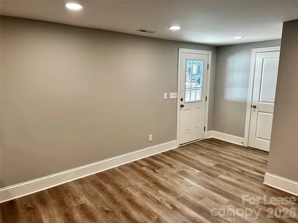 an empty room with wooden floor and windows