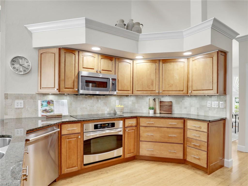 6862 Mill Run Road Naples, FL 34109 - Photo 14 of 50 Kitchen with ceiling fan with notable chandelier, stone counters, stainless steel fridge, light wood-type flooring, and tasteful backsplash