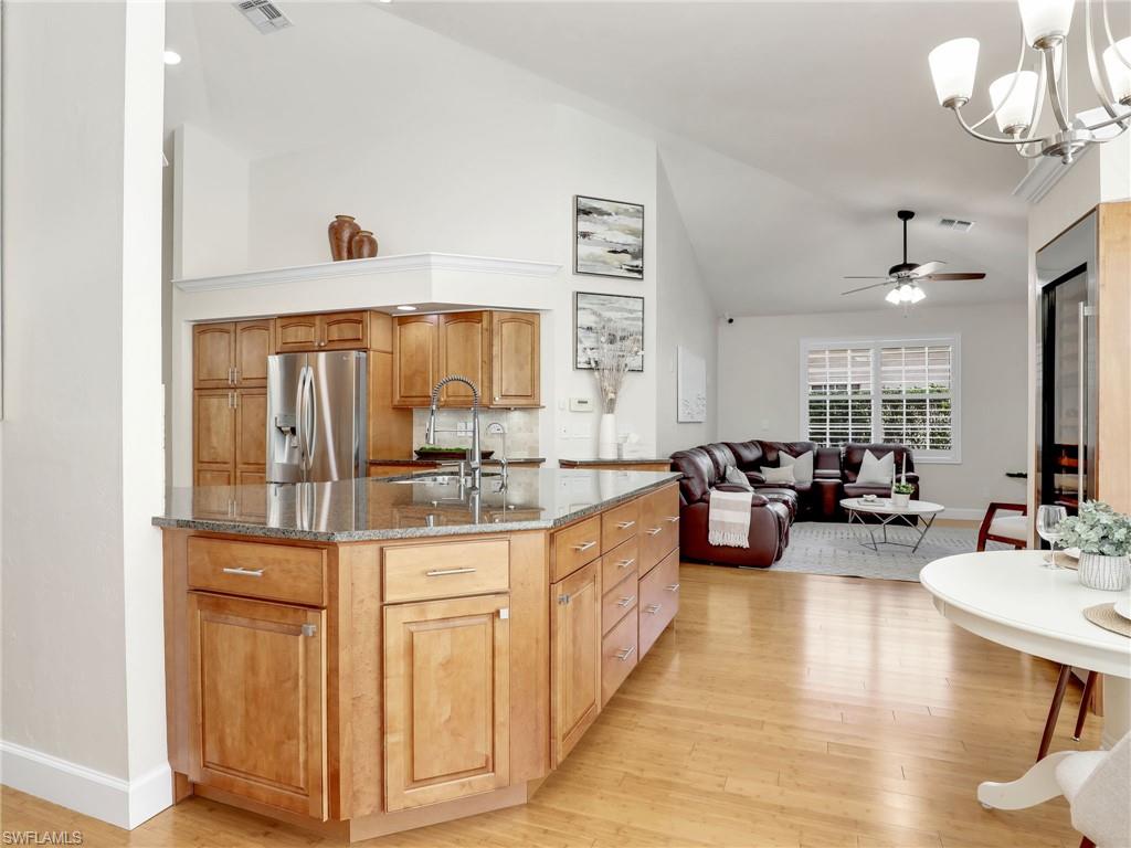 6862 Mill Run Road Naples, FL 34109 - Photo 15 of 50 Kitchen with high vaulted ceiling, stainless steel appliances, backsplash, and light hardwood / wood-style floors