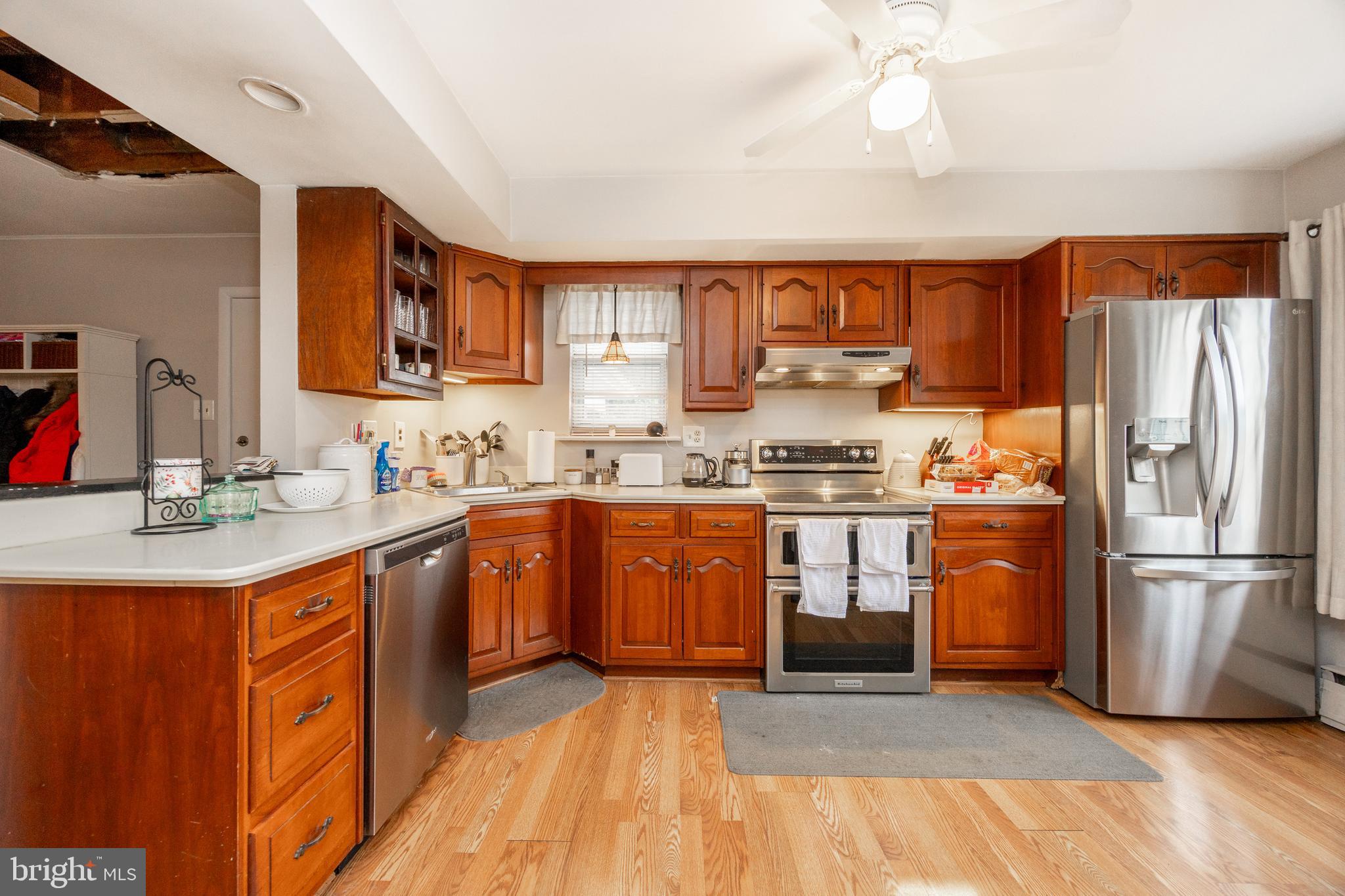 149 Conestoga Road Malvern, PA 19355 - Photo 6 of 43 a kitchen with stainless steel appliances granite countertop a refrigerator a sink dishwasher a stove with wooden cabinets and floor