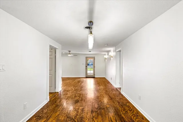 a view of a hallway with wooden floor and chandelier