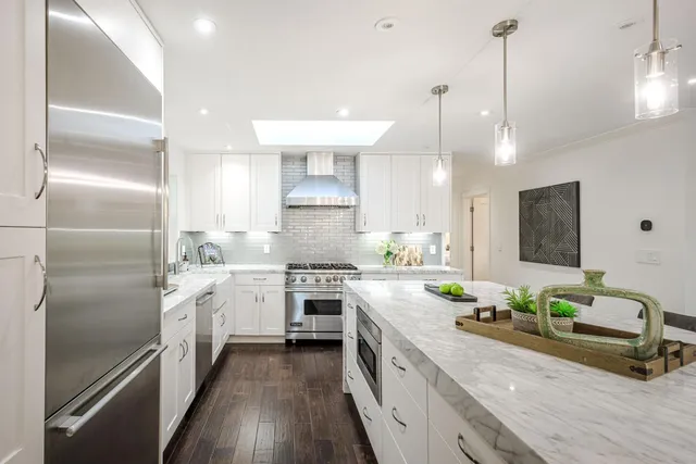 a large kitchen with granite countertop a large counter top a sink stainless steel appliances and cabinets