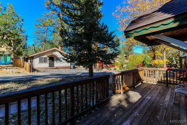 a view of house with wooden deck and outdoor seating