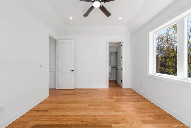 a view of a big room with wooden floor and a chandelier fan