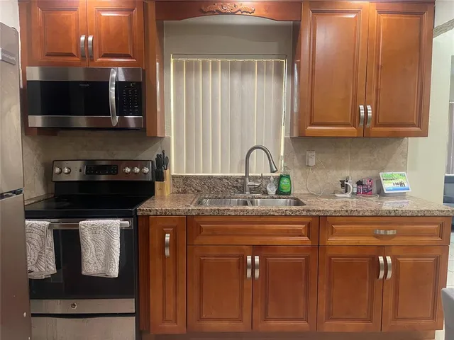 a kitchen with stainless steel appliances granite countertop a refrigerator a stove and a sink