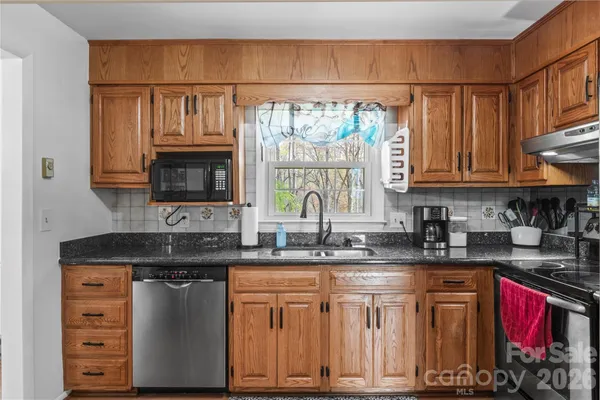 a kitchen with stainless steel appliances granite countertop a sink a stove cabinets and a microwave