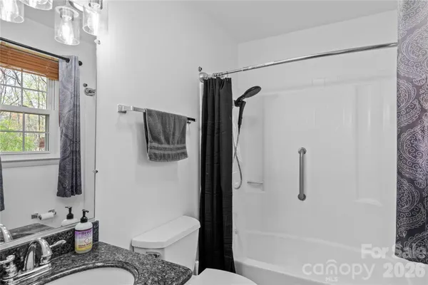a bathroom with a granite countertop sink a mirror and shower